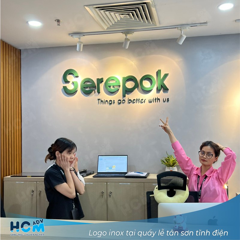 Logo inox gắn tại quầy lễ tân văn phòng startup với thiết kế tối giản.