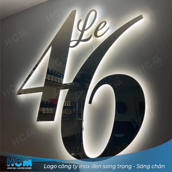 Nhân viên đang lắp logo inox mạ đen tại sảnh công ty bất động sản.
